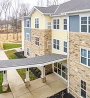 Columbus apartment for rent - A building with a yellow and blue exterior and a covered walkway.