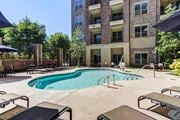 Chattanooga apartment for rent - A large swimming pool surrounded by lounge chairs and umbrellas in front of a multi-story apartment building.