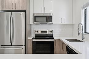Miami Gardens apartment for rent - A modern kitchen with a stainless steel refrigerator, microwave, oven, and sink.at The Villages at Miami Gardens, Miami Gardens