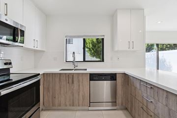 Miami Gardens apartment for rent - A modern kitchen with a stainless steel dishwasher and wooden cabinets.