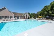 Greensboro apartment for rent - A large swimming pool in front of a building with a thatched roof.