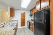 Warner Robins apartment for rent - A black refrigerator is in a kitchen with wooden cabinets.