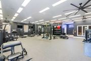 Warner Robins apartment for rent - A spacious gym with various exercise equipment and a ceiling fan.