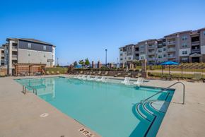 Commerce apartment for rent - A large swimming pool with lounge chairs and apartment buildings in the background.