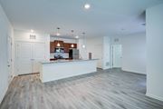 Commerce apartment for rent - A spacious kitchen with white cabinets and a wooden floor.