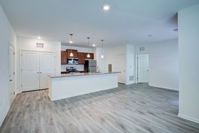 Commerce apartment for rent - A spacious kitchen with white cabinets and a wooden floor.