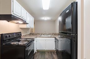 Aiken apartment for rent - A black stove top oven with four burners and a black refrigerator in a kitchen.
