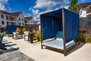 Madison apartment for rent - an outdoor lounge area with a blue tent in front of an apartment building at Farmhaus Apartments, Madison, Alabama
