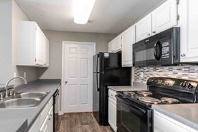 Warner Robins apartment for rent - A kitchen with black appliances and white cabinets.