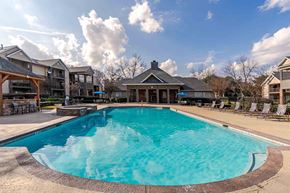 Warner Robins apartment for rent - A large swimming pool in the middle of a resort surrounded by chairs.