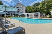 Chattanooga apartment for rent - A swimming pool surrounded by sun loungers and umbrellas in front of apartment buildings.