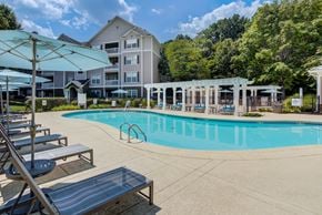 Chattanooga apartment for rent - A swimming pool surrounded by sun loungers and umbrellas in front of apartment buildings.