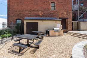 Petersburg apartment for rent - A brick building with a black fence and a picnic table in front at Mayton Transfer Lofts in VA 23803
