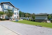Newnan apartment for rent - A large building with a blue and white exterior is surrounded by a well-maintained lawn and a clear blue sky.