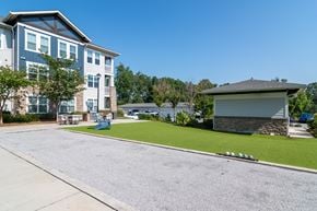 Newnan apartment for rent - A large building with a blue and white exterior is surrounded by a well-maintained lawn and a clear blue sky.