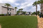 Santa Rosa Beach apartment for rent - A grassy area with a building and palm trees in the background.