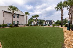Santa Rosa Beach apartment for rent - A grassy area with a building and palm trees in the background.