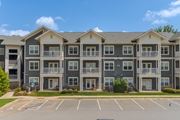 Arden apartment for rent - Apartment building with grey and white exterior and a parking lot in front.