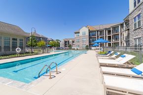 Williamsburg apartment for rent - A swimming pool with sun loungers and apartment buildings in the background.