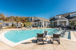Knoxville apartment for rent - a large swimming pool with chairs and a house in the background at Village at Westland Cove Apartments, Knoxville, 37922