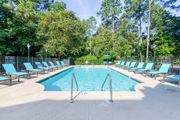 Aiken apartment for rent - A large swimming pool surrounded by trees and lounge chairs.