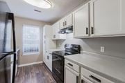 Aiken apartment for rent - A kitchen with white cabinets and a black fridge.