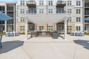 Chester apartment for rent - A patio with a white pergola and blue chairs is surrounded by apartment buildings.