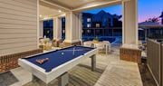 Richmond apartment for rent - a pool table on a patio with a pool house in the background at Canopy at Ginter Park Apartments in Richmond, VA 23227
