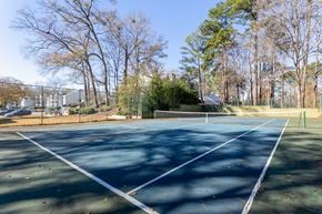 Macon apartment for rent - A tennis court surrounded by trees and a fence.