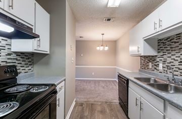 Macon apartment for rent - A kitchen with a black stove top oven and white cabinets.