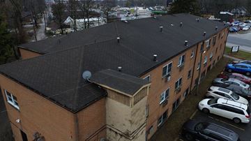 Columbus apartment for rent - An aerial view of a parking lot with cars and a building with a black roof.