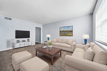 Tuscaloosa apartment for rent - A living room with a large couch, a coffee table, and a painting on the wall.