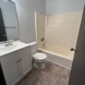 Dekalb apartment for rent - A white toilet sits in a bathroom next to a sink and a bathtub.
