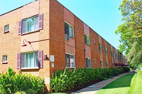 St. Louis apartment for rent - a brick building with purple shutters and a sidewalk in front of it