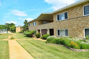 Olivette apartment for rent - a large brick apartment building with a lawn and flowers in front of it