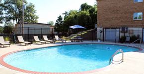 St. Louis apartment for rent - a swimming pool with chaise lounge chairs and a building in the background