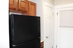 St. Louis apartment for rent - A black fridge in a kitchen with wooden cabinets.
