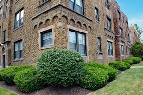 St. Louis apartment for rent - A row of red brick buildings with green bushes in front.