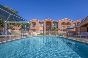 Victorville apartment for rent - A swimming pool in front of a building with a clear blue sky.