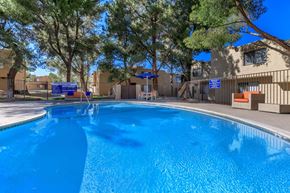 Barstow apartment for rent - A swimming pool surrounded by trees and a building in the background.