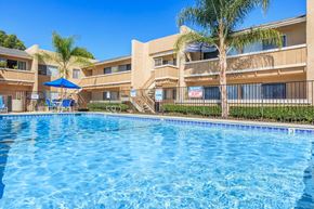 Vista apartment for rent - A swimming pool in front of a building with a blue umbrella.