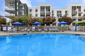 Las Vegas apartment for rent - a large pool with chairs and umbrellas in front of an apartment building