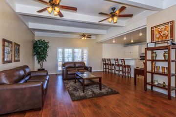 Vista apartment for rent - A living room with brown leather furniture and a ceiling fan.