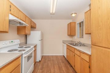 Barstow apartment for rent - A kitchen with wooden cabinets and a white stove top oven.
