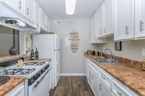 Riverside apartment for rent - a kitchen with white cabinets and a stove and a sink