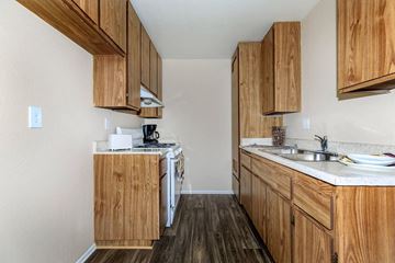 Barstow apartment for rent - A kitchen with wooden cabinets and a white dishwasher.