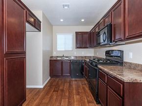 Lompoc apartment for rent - a kitchen with wooden cabinets and black appliances