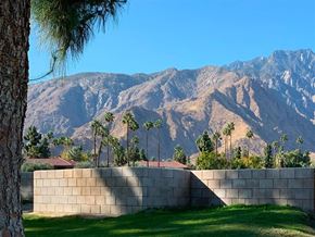 Palm Springs apartment for rent - A wall separates a grassy area from a mountain.