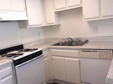 Palm Springs apartment for rent - A white kitchen with a black stove top and a white dishwasher.