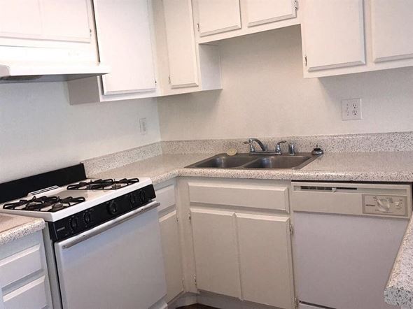 Palm Springs apartment for rent - A white kitchen with a black stove top and a white dishwasher.